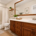 This staged full bathroom highlights quality wood cabinetry, generous countertop space, tiled flooring, modern fixtures, and a clean, inviting design that complements the basement living area.