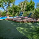 Enjoy comfortable outdoor gatherings beneath the spacious covered patio complete with ceiling fan, conversation seating, and easy access to the custom pool and backyard retreat.