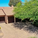 This aerial front view emphasizes the generous paver driveway, three-car garage, mature shade tree, and attractive desert landscaping that enhance the curb appeal of this beautifully maintained Scottsdale home.
