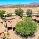 An expansive aerial image highlights the surrounding Scottsdale community, nearby mountain vistas, mature trees, and the home's prime location. The view showcases an inviting neighborhood with attractive homes and scenic desert surroundings.