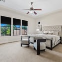 The expansive primary bedroom offers generous proportions, large windows, plush carpeting, and plenty of room for a sitting area. This relaxing retreat enhances the luxury lifestyle found throughout the home.