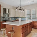 An oversized island, quartz countertops, premium stainless steel appliances, double ovens, gas cooktop, and custom cabinetry combine to create a stunning gourmet kitchen for everyday living and entertaining.