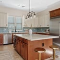 An open view of the gourmet kitchen highlights the oversized island, stainless steel appliances, quartz countertops, custom cabinetry, designer lighting, and spacious layout perfect for gatherings.