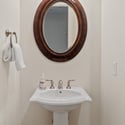 This well-appointed powder room features a pedestal sink, elegant lighting, and timeless finishes, providing a stylish and convenient space for visitors.