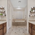 Dual vanities, custom cabinetry, elegant stone flooring, a soaking tub, and premium finishes create a luxurious primary bathroom that perfectly complements this exceptional Scottsdale home.