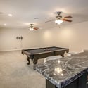 Designed for entertaining, this expansive basement combines open recreation space, a billiards area, recessed lighting, ceiling fans, and a custom wet bar for memorable gatherings.