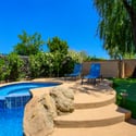 The raised spa and expansive lounging deck provide the perfect place to relax while surrounded by mature trees, artificial turf, and lush landscaping in this Scottsdale backyard.
