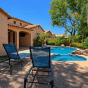 Lounge beside the sparkling pool from the spacious sun deck featuring comfortable seating, tropical landscaping, and a relaxing outdoor environment designed for Scottsdale living.