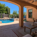 The covered patio creates an inviting outdoor living space with comfortable seating, pool views, shaded entertaining areas, and seamless access to the beautifully landscaped backyard.