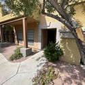 The private front entrance is framed by mature landscaping and desert-friendly grounds, creating a welcoming first impression in this well-maintained gated community.