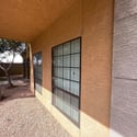 The covered front patio provides a relaxing outdoor sitting area surrounded by mature landscaping and attractive desert scenery within the gated community.