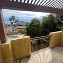 The spacious upper balcony with pergola offers relaxing views of the community pool, mature landscaping, and nearby mountain scenery, perfect for enjoying Arizona mornings and evenings.