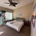 This spacious primary suite features vaulted ceilings, large windows, plush carpeting, and direct access to the private balcony for indoor-outdoor living.