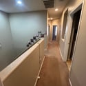 The upstairs landing overlooks the main living area and connects the secondary bedrooms, laundry room, and primary suite with an open, airy design.