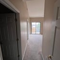 The hallway leads into the spacious primary suite, showcasing the home's functional layout, vaulted ceilings, and easy access to the private balcony and ensuite bathroom.