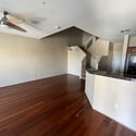 The open living room offers soaring ceilings, attractive wood flooring, ceiling fan, and seamless access to the kitchen, creating a welcoming space designed for comfortable everyday living.