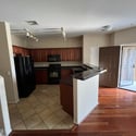 Designed for convenience, the kitchen features generous cabinetry, black appliances, durable tile flooring, and a breakfast bar that connects effortlessly to the open-concept living area.