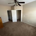 A spacious secondary bedroom with vaulted ceilings, plush carpeting, ceiling fan, and a large closet offers flexible living options for guests, family members, or a home office.