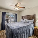 Featuring wood-look flooring, a large window, ceiling fan, and neutral d cor, this comfortable bedroom provides flexible living options for guests, family members, or remote work.