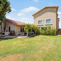 A spacious backyard with a large grassy area, mature trees, covered entertaining patio, and attractive landscaping provides the perfect outdoor environment for relaxing or hosting family and friends in Glendale.