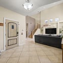 The spacious foyer introduces the home's open-concept design with soaring ceilings, abundant sunlight, neutral finishes, and beautiful tile flooring that seamlessly connects the main living spaces.