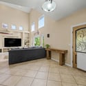 Welcome guests through a beautiful custom entry door into a bright foyer featuring soaring ceilings, neutral finishes, and an open layout that highlights the home's spacious and inviting design.