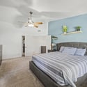 This generously sized bedroom offers a bright and airy atmosphere with vaulted ceilings, neutral colors, ceiling fan, and ample space for large furnishings while maintaining a relaxing feel.