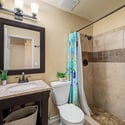 Enjoy an updated guest bathroom with a granite vanity, framed mirror, modern lighting, and a tiled walk-in shower designed with attractive finishes and everyday functionality.