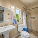This well-appointed bathroom includes a pedestal sink, updated fixtures, tiled walk-in shower, and neutral finishes that complement the home's modern updates throughout.