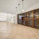 Floor-to-ceiling custom cabinetry with glass display shelves and integrated wine storage adds sophistication while providing exceptional storage and entertaining space within the home's open layout.