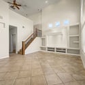 Oversized windows and soaring ceilings flood the great room with natural light, while the custom entertainment center creates an inviting focal point for comfortable everyday living.