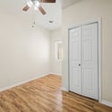 A bright secondary bedroom with updated flooring, vaulted ceilings, ceiling fan, and closet space provides comfort and versatility for guests, family, or a dedicated workspace.