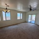 Large living room featuring expansive windows, ceiling fan, and patio access that creates a bright, airy atmosphere. Perfect for relaxing or hosting guests.