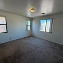 Bright secondary bedroom with large windows, comfortable carpeting, and flexible space suitable for guests, family, or a home office setup.