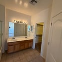 Primary bathroom with dual sinks, expansive vanity, walk-in closet access, and ample storage. Designed to provide convenience and functionality for everyday living.