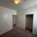 Spacious bedroom with plush carpeting, large closet, and flexible floor plan suitable for a guest room, office, or personal retreat.