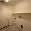 Dedicated laundry and utility room with washer and dryer hookups, storage shelf, and convenient access for efficient household tasks.
