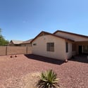 Private fenced backyard with attractive desert landscaping and ample outdoor space, providing a peaceful setting that's easy to maintain in this Phoenix rental.