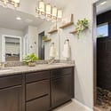 Primary bathroom features a dual vanity, a spa-like walk-in shower paved in river rocks, and an oversized closet that simplifies daily routines.