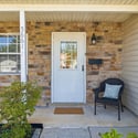 Welcoming entryway features a cozy chair and tasteful landscaping, perfect for enjoying outdoor moments.