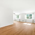 Spacious living area with abundant natural light, featuring large windows and a flexible layout for various uses.