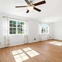 Bright, open living space featuring large windows and a ceiling fan, perfect for versatile furnishings.