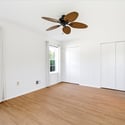 Bright and spacious bedroom featuring large windows, ample storage, and a modern ceiling fan.