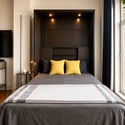 Bright and cozy bedroom featuring a modern foldaway bed and large windows bringing in natural light.