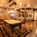 Discover a vibrant game room featuring a pool table, game console, bar, and rustic brick accents for entertainment.