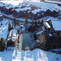 This modern property features a spacious outdoor pool surrounded by snow-covered landscape and nearby amenities.