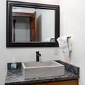 Lower-level powder room bath featuring a sleek countertop, minimalist sink, and ample natural light, perfect for daily routines.