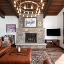 Spacious great room with mountain views, a stone fireplace, and modern fixtures, perfect for gatherings. The open floor plan connects the great room to the kitchen and dining areas. Sliding glass doors open to a back deck featuring Emerald Mountain views.