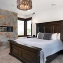 Luxurious primary bedroom featuring a stunning stone fireplace and modern lighting, a five-piece en suite bath, mountain views, and a private balcony.