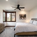Modern bedroom with ample natural light, featuring a cozy bed, sleek furniture, and scenic window views.
